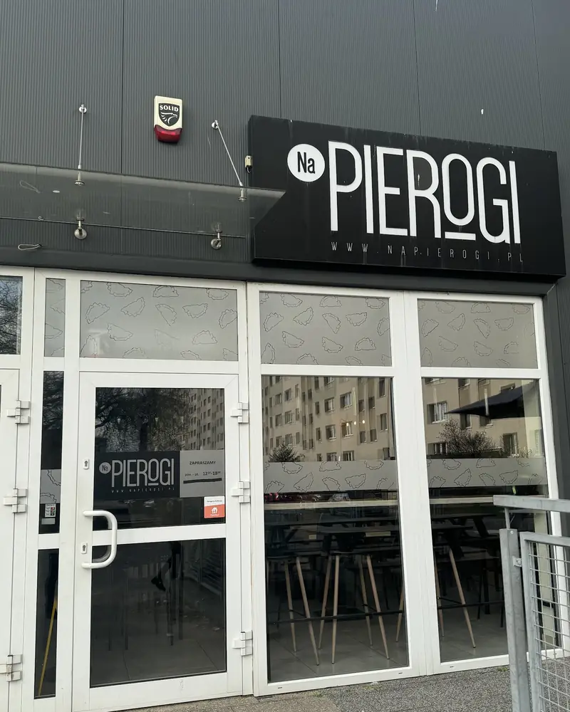 Czarny szyld Na Pierogi nad wejściem w Hali Gulden